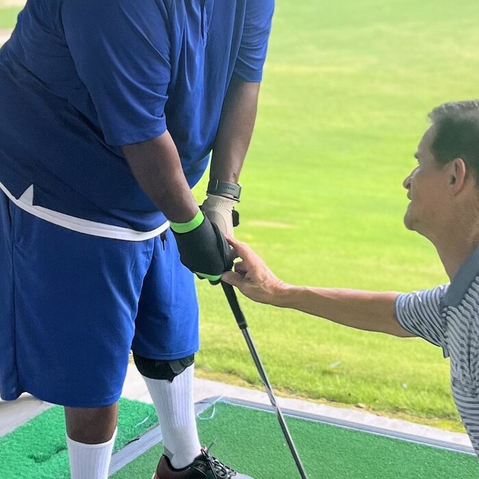 Marty Turcios adjusting a participant's hands on the club at a Power Tee mat
