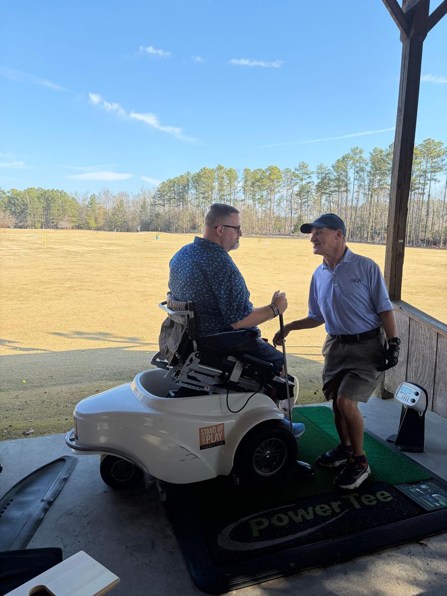 An MTTG participant using an adaptive golf cart talks with Marty Turcios at the driving range