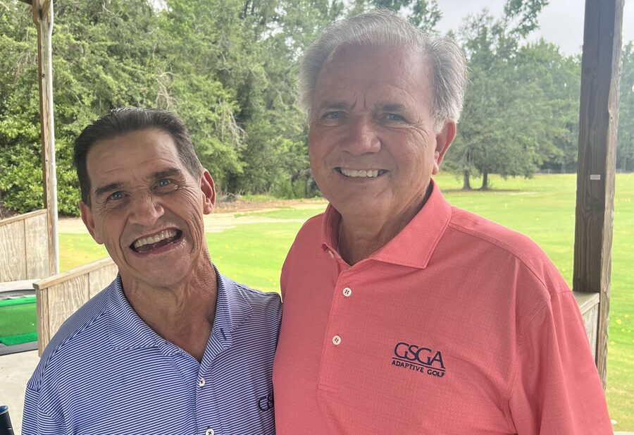 Marty Turcios and GSGA Adaptive Golf instructor Doug Cameron smiling together at a driving range